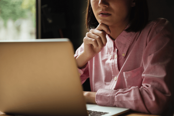 Image d’une femme en train de réfléchir devant son ordinateur